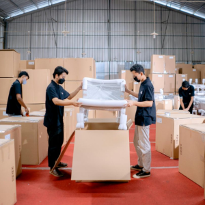 men in black uniforms place chair in box in a warehouse full of boxes