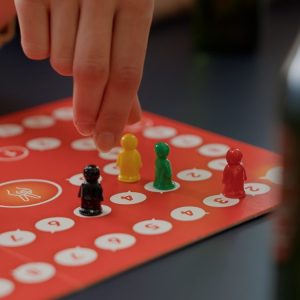 young people playing a board game with an hour glass