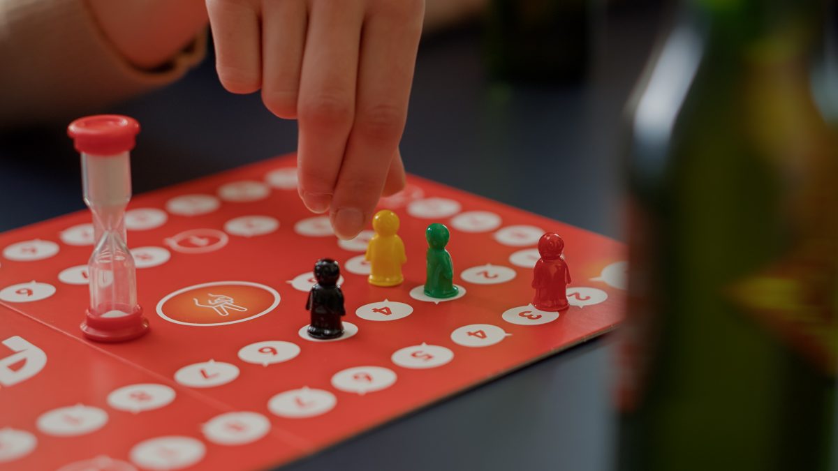 young people playing a board game with an hour glass