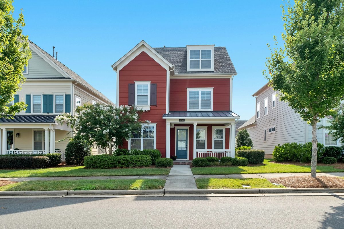red brick house with blue sky and green yard ans sidewalk