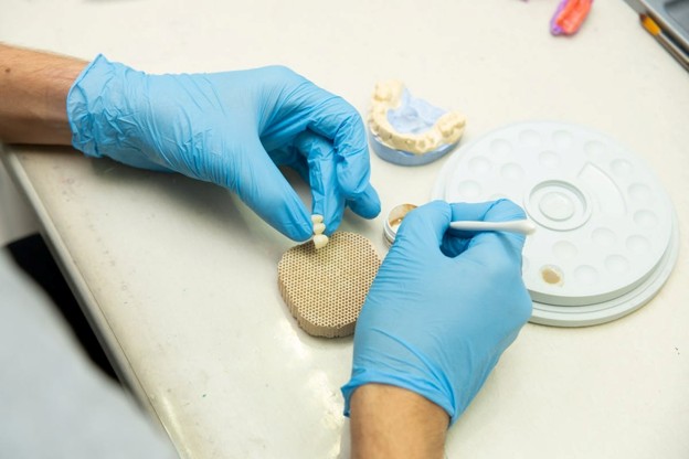 hands with gloves holding dental teeth crowns