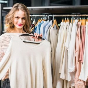 woman holding a shirt from a clothing rack