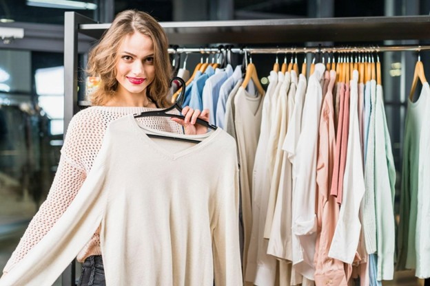woman holding a shirt from a clothing rack
