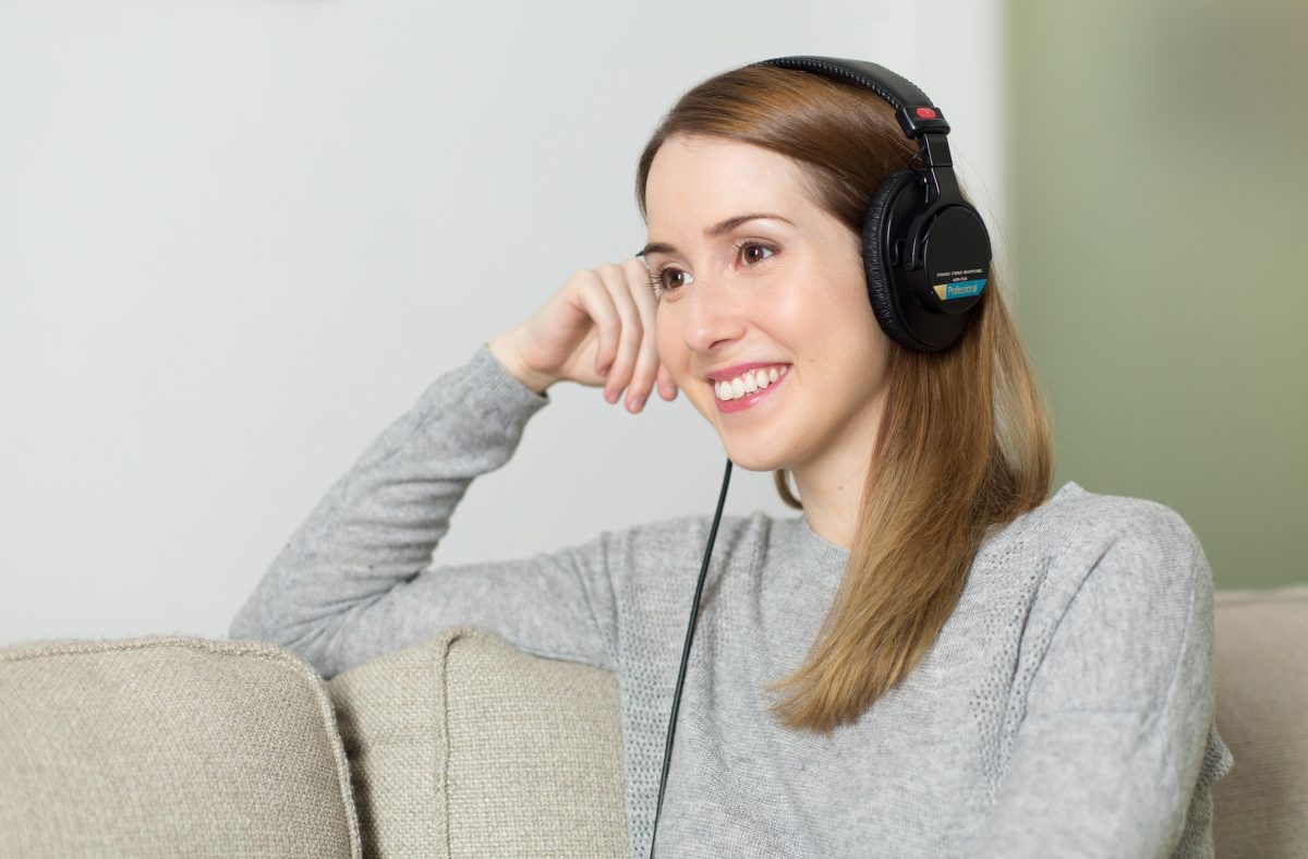 woman wearing headphones while sitting on a couch