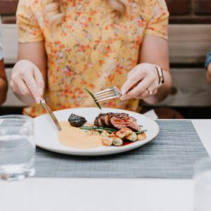 close up of lady eating a meat plate at a restaurant