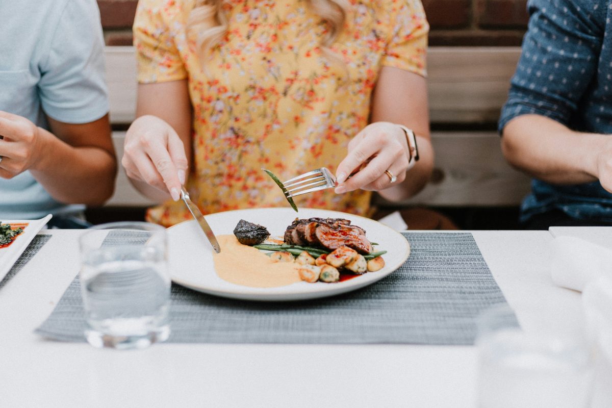 close up of lady eating a meat plate at a restaurant