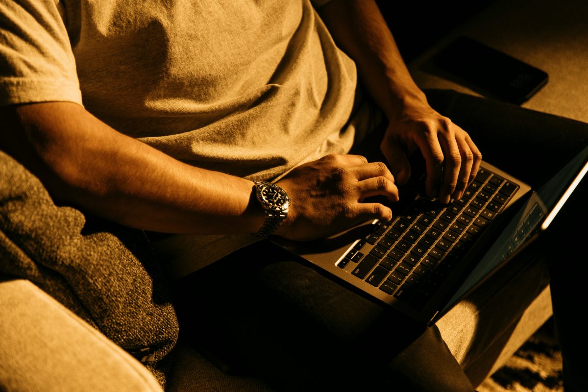 man sitting on a couch using a laptop computer