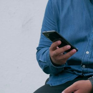 person in blue denim jacket holding phone