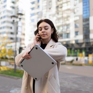 woman looking at a watch while on the phone crossing a street