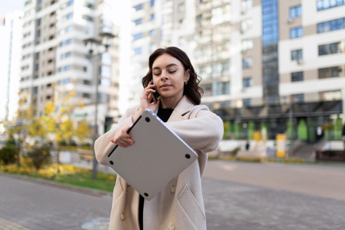 woman looking at a watch while on the phone crossing a street