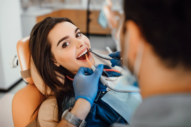 woman looking at camera while sitting in dentsit chair getting dental procedure
