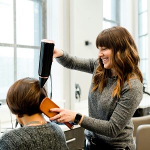 woman holding hair dryer and brushing a clients hair