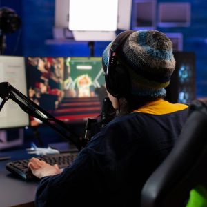 Caucasian player wearing headphones talking with other players while playing professional shooter games in online tournament. Gamer making online videogames with new graphics on powerful computer