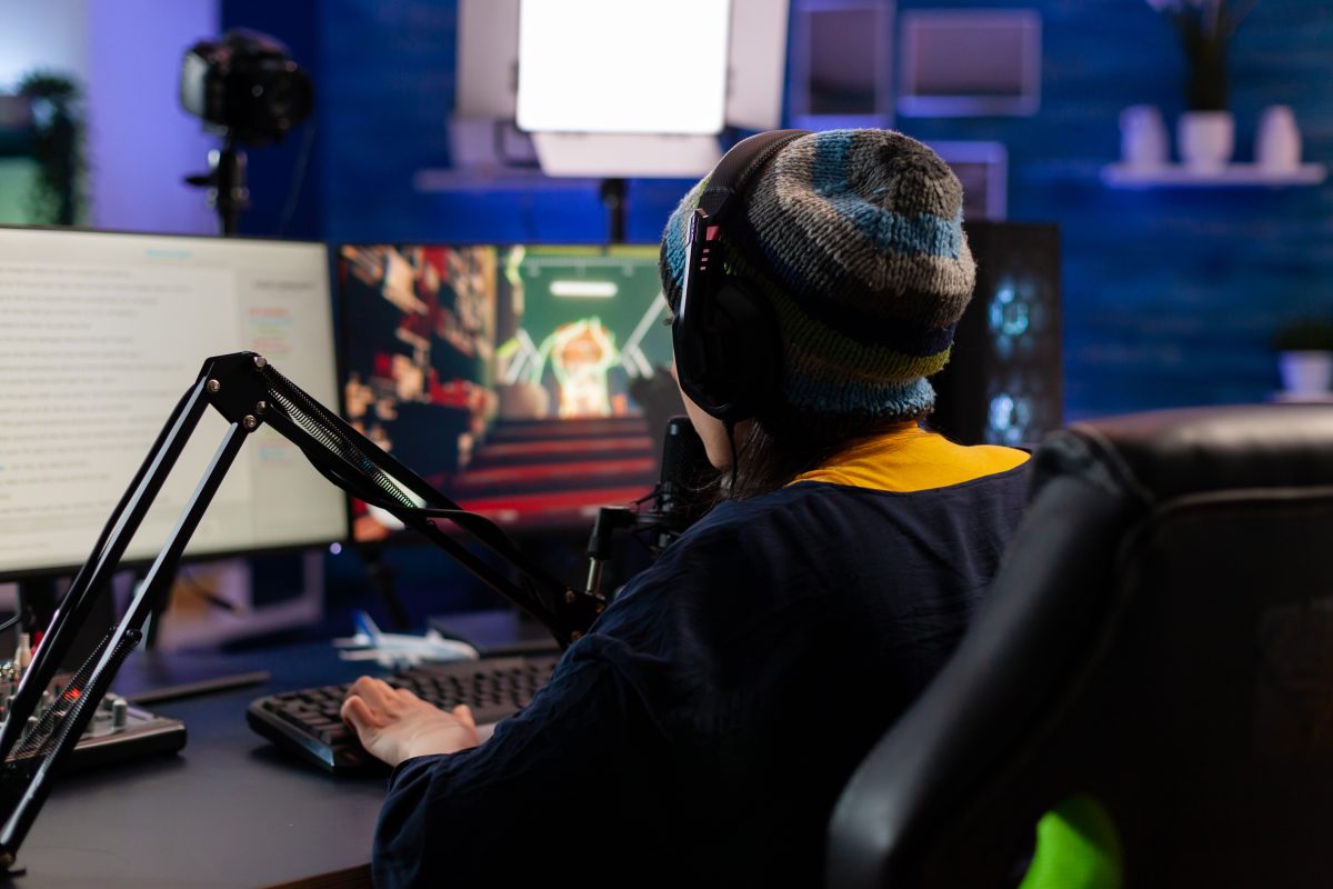  Caucasian player wearing headphones talking with other players while playing professional shooter games in online tournament. Gamer making online videogames with new graphics on powerful computer