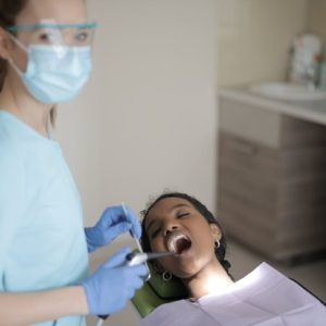 dental assistant looking at the camera with dental patient in chair for checkup