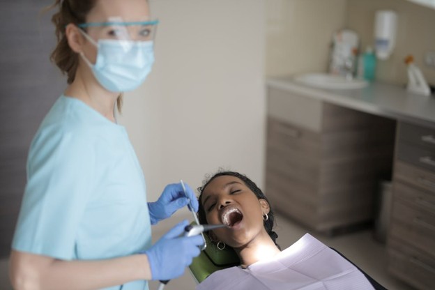 dental assistant looking at the camera with dental patient in chair for checkup 