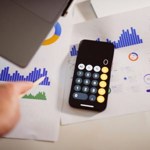 calculator sitting on a table with charts and laptop
