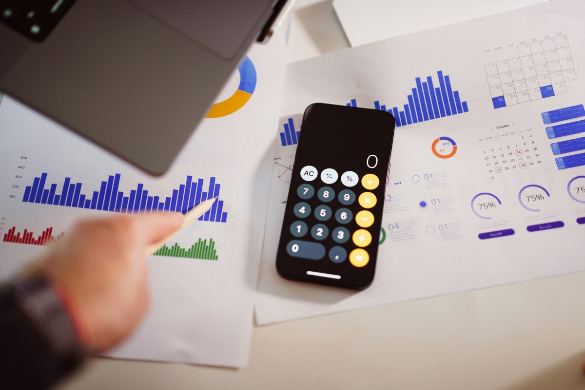 calculator sitting on a table with charts and laptop