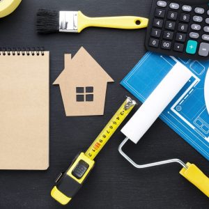 blue print house with tools and an empty notepad on a black table