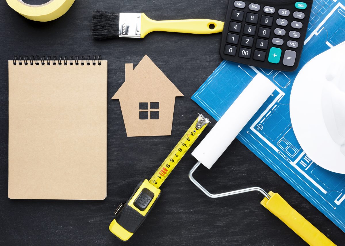 blue print house with tools and an empty notepad on a black table
