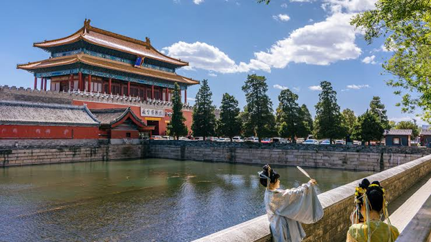 chinese women take a picture near chinese building on water