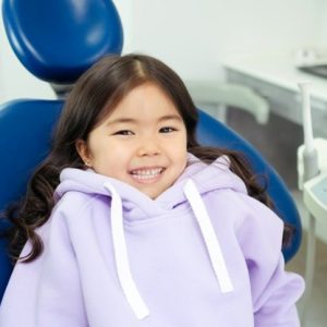 girl in purple sweatshirt sitting in a dental chair