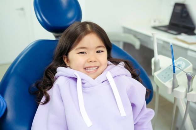 girl in purple sweatshirt sitting in a dental chair