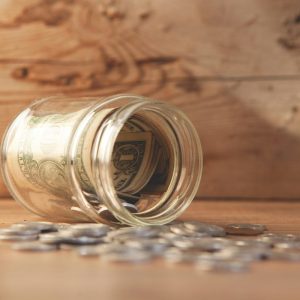 jar with money and coins spilled on the table