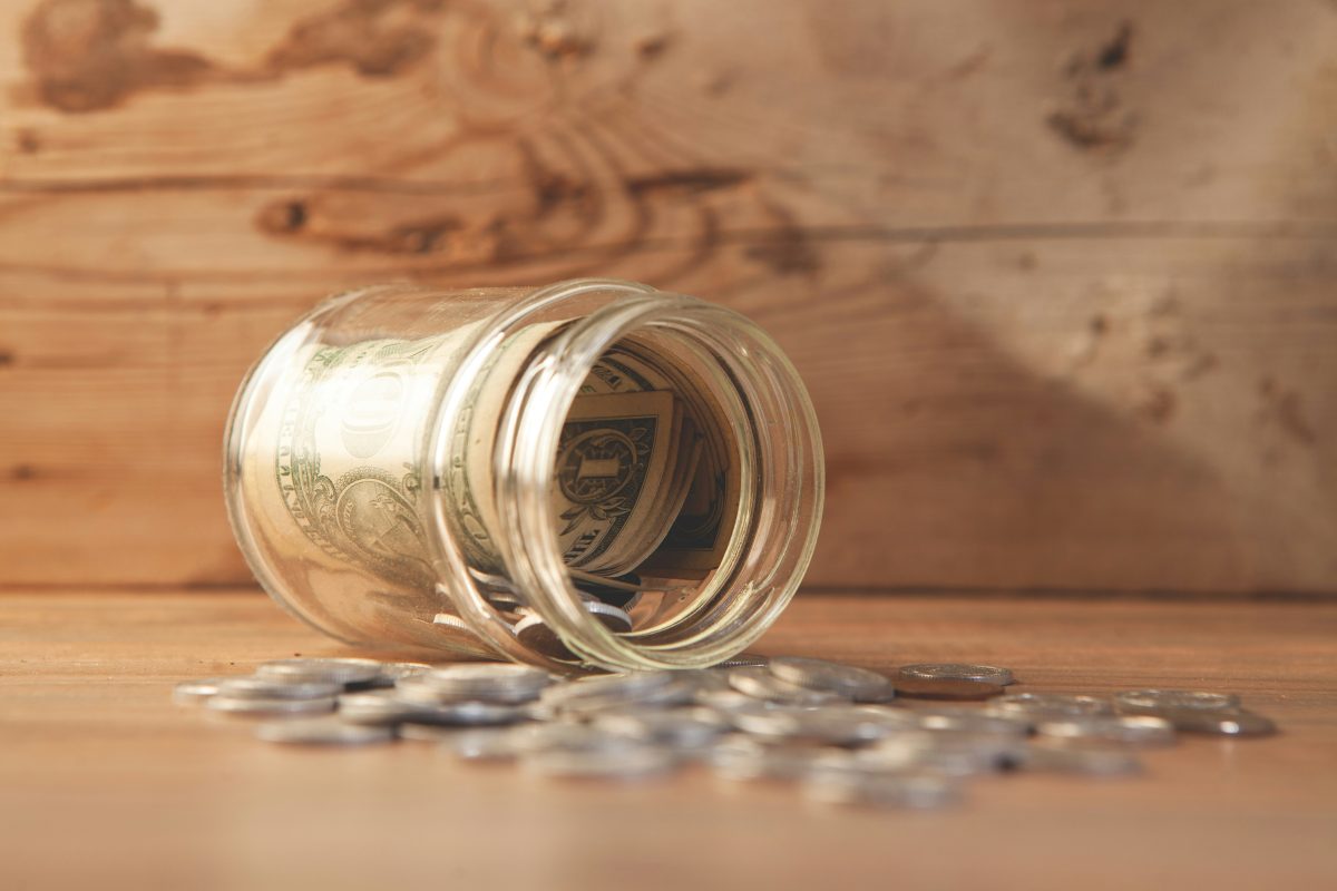 jar with money and coins spilled on the table