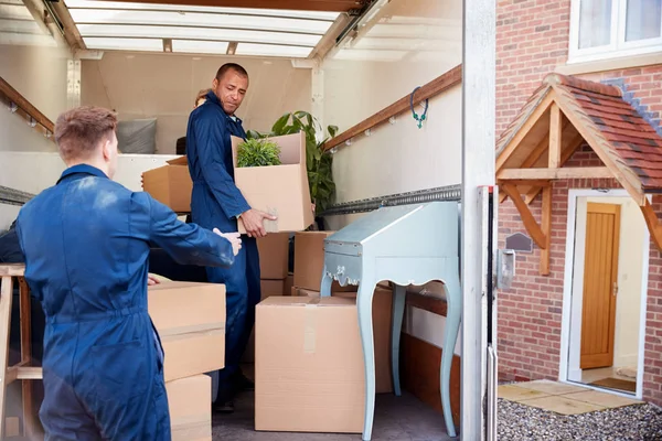 two men moving boxes from truck to home