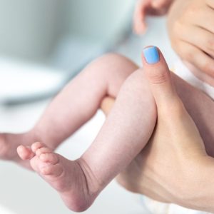 close up of newborn baby legs and moms hands