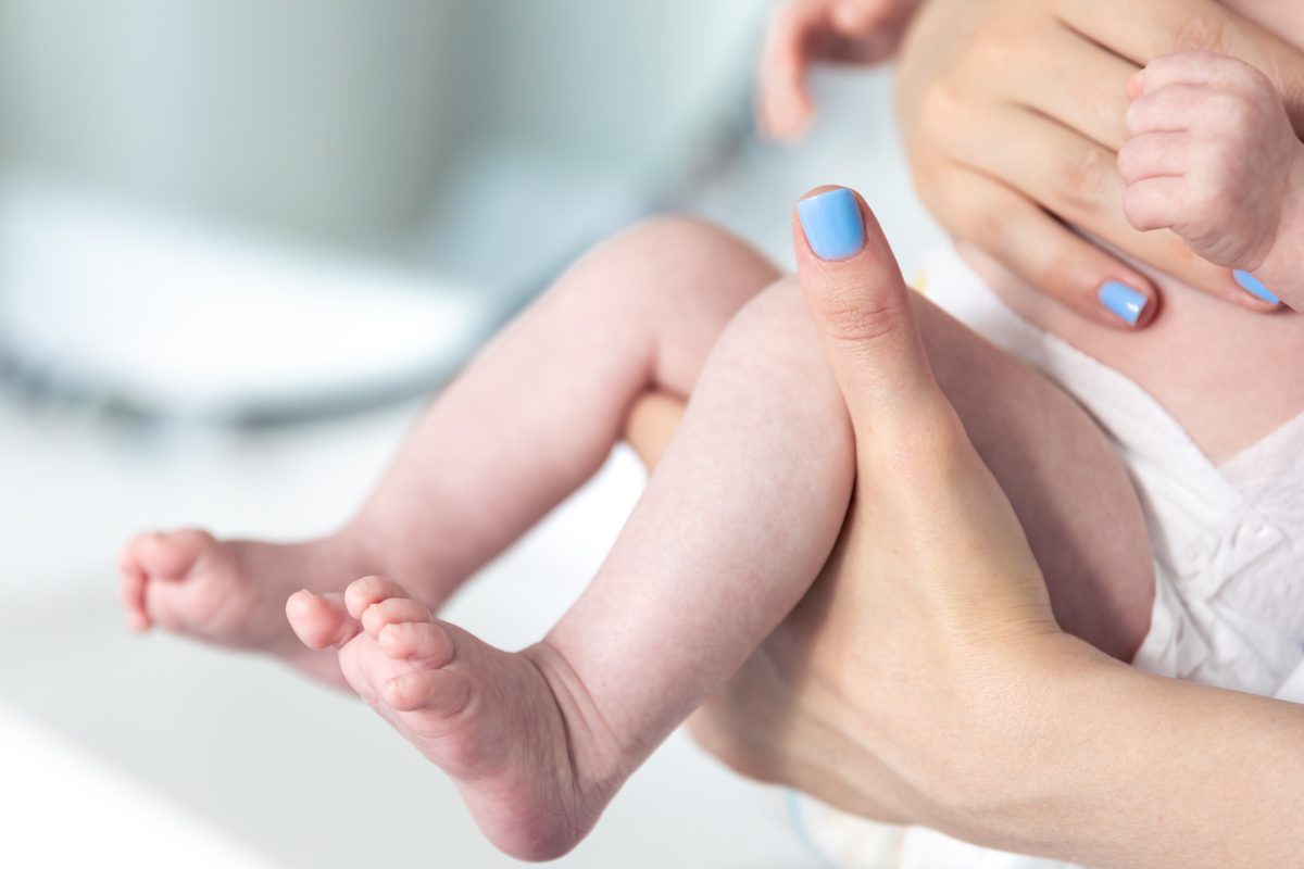 close up of newborn baby legs and moms hands
