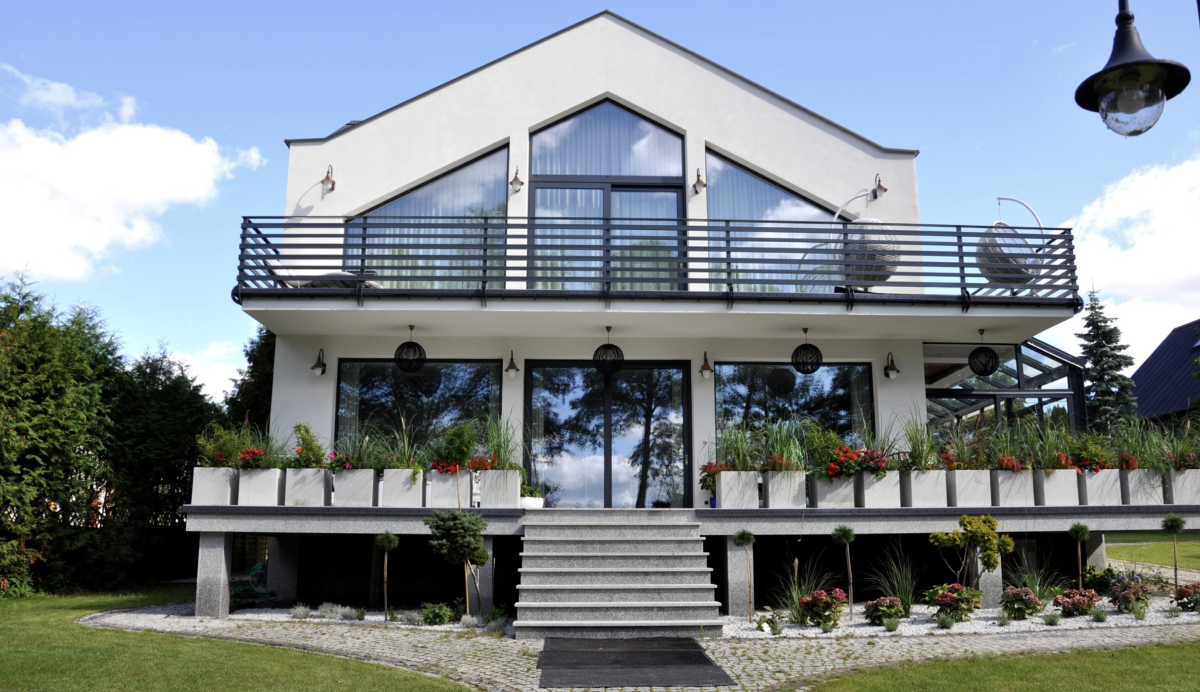two story home with balcony and lots of windows and plants