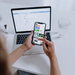 woman scrolling on phone with laptop on table