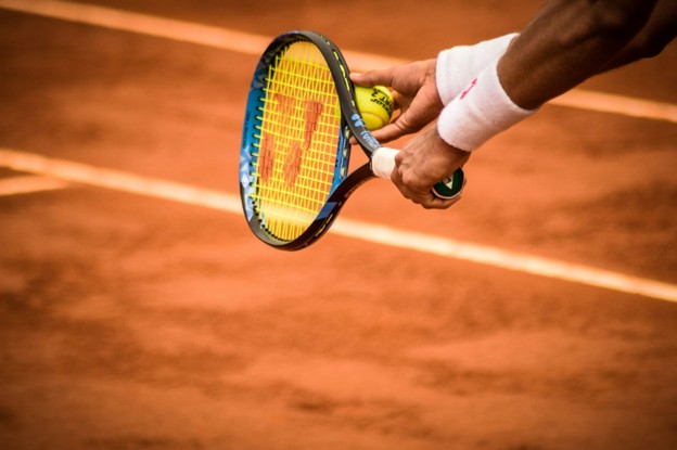 tennis player holding racquet and ball on court