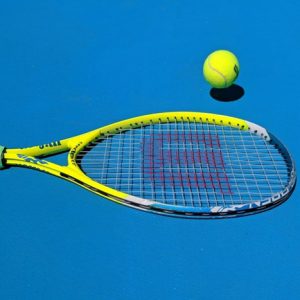 tennis racquet and ball on blue court
