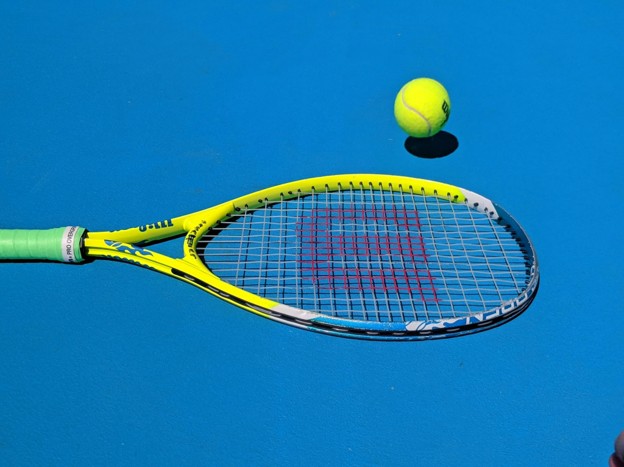 tennis racquet and ball on blue court