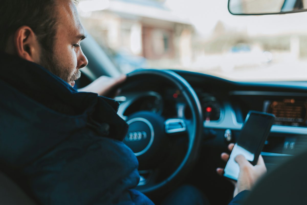 man looking at phone while driving