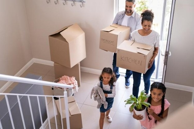 couple with children move boxes into a new home