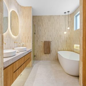 Modern bathroom with double sinks, freestanding tub, and wooden accents.