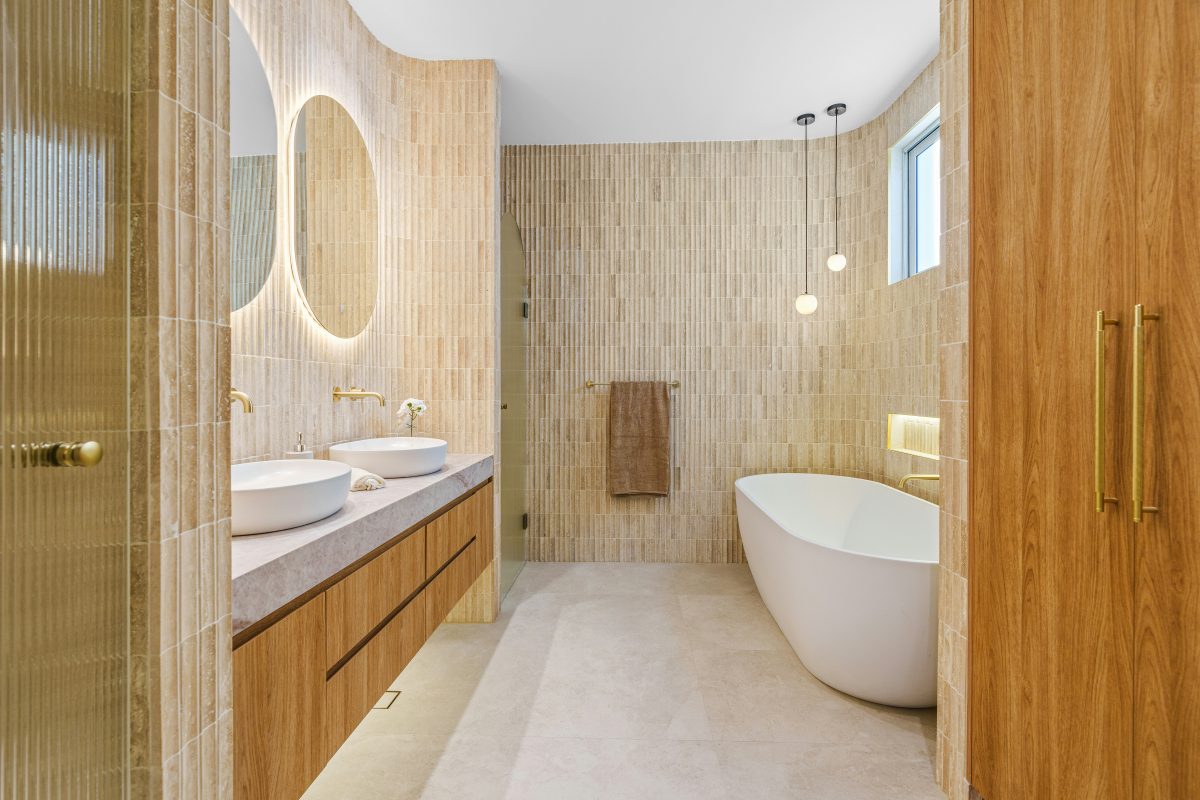 Modern bathroom with double sinks, freestanding tub, and wooden accents.