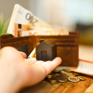 man holding tiny home with wallet in background