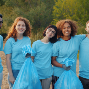 group of people in blue pose for camera while holding blue trash bags