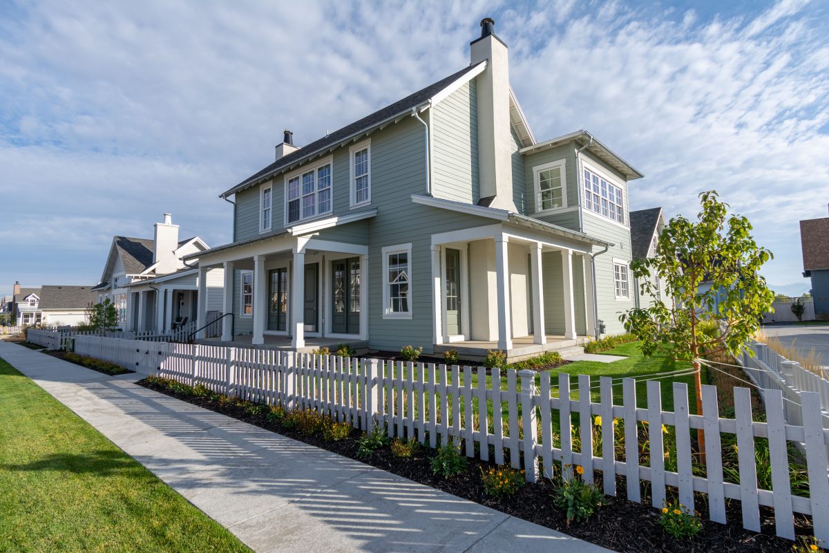 beige green house behind white pickett fence