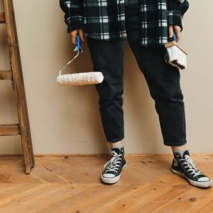 A person holding a paint roller and brush during a home renovation project.