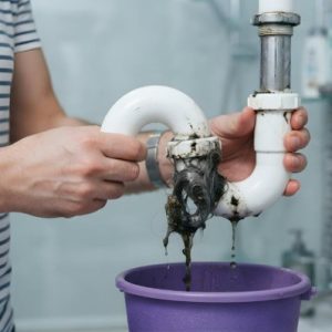 man trying to fixing leaking pipe in bathroom