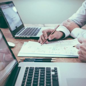 professionals look over paperwork with laptops