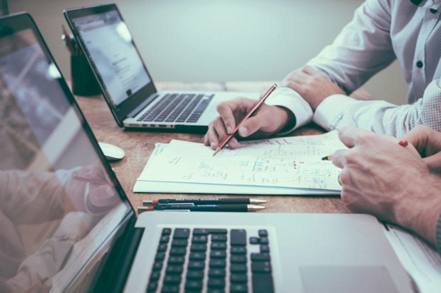 professionals look over paperwork with laptops