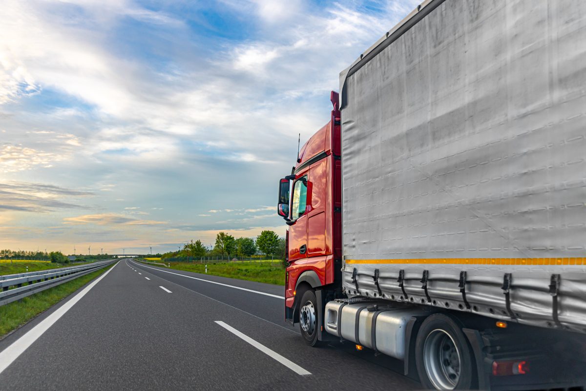 Red cargo truck on highway freight transport scene with open road