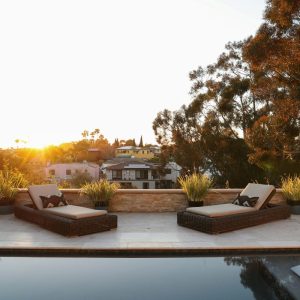 a pool with two lounge chairs and a view of a house